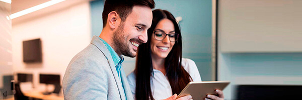 Cash Pooling - Hombre de traje sonriendo junto a una mujer de gafas sonriendo en oficina