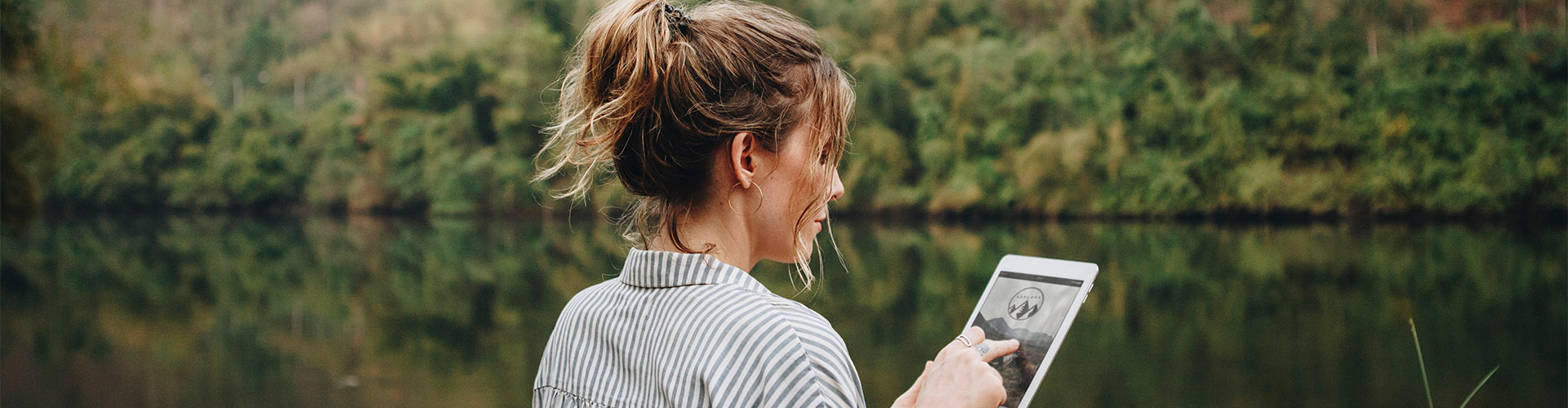 Préstamo Joven In - Una mujer usando una tableta digital en plena naturaleza