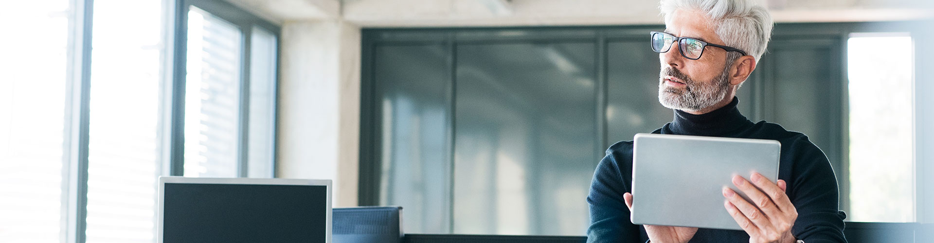 Bolsa y Mercados Empresas - Hombre de negocios de mediana edad con gafas y una tablet en las manos en la oficina