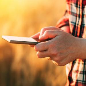 Apps moviles ruralvia app - Manos cogiendo un móvil para consultar la evolucion de sus inversiones
