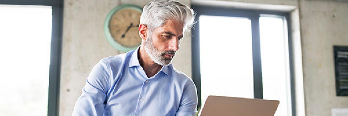 Servicio de Valores Online - Hombre de negocios sentado con su portatil en la oficina Servicio de Valores Online - Hombre de negocios sentado con su portatil en la oficina